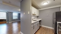 Located at 86 Hillman St in Springfield's Silverbook neighborhood, this two-floor residence showcases a clean, modern aesthetic with consistent design details throughout. The kitchen is thoughtfully appointed with white upper cabinetry, gray lower cabinets, white subway tile backsplash, light quartz countertops, a stainless steel sink, and stainless steel appliances including a refrigerator, range, and dishwasher. Warm, wood-tone luxury vinyl plank flooring runs throughout the space, complementing the cool gray walls and crisp white trim found in every room. The main living area on the lower floor is generously proportioned, featuring large windows that invite natural light and views of the surrounding neighborhood. A sleek staircase with metal railings connects the two floors. The upper level offers additional living and bedroom spaces, each with hardwood-style flooring, natural window light, and a consistent neutral color palette. The bathroom features a full tub-shower combination with white tile surround and chrome fixtures. Textured ceilings and clean white baseboards complete the refined yet understated interior throughout both floors, creating a cohesive and well-maintained living environment.