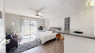 Located at 4500 Woodman Ave in the heart of Sherman Oaks, Los Angeles, this well-appointed one-bedroom, two-bathroom unit offers a thoughtfully designed single-floor layout that maximizes every square foot. The exterior of the building showcases a classic white stucco facade with decorative lattice details and navy awnings, lending a distinct character to the property.

The generously sized primary bedroom serves as the centerpiece of the unit, featuring warm wood-look flooring, a ceiling fan with light fixture, and sliding glass doors that open onto a private balcony, allowing natural light to fill the space. Built-in cabinetry and two closets — one of which is a walk-in — provide ample storage. A cozy seating area within the bedroom adds versatility to the room.

The kitchen is efficiently designed with white shaker-style cabinetry, dark countertops, stainless steel appliances including a refrigerator and over-the-range microwave, and a breakfast bar that doubles as a dining area. Both bathrooms are finished with white vanities, gray countertops, large mirrors, and wood-look flooring, with one bathroom featuring a shower-tub combination. The overall aesthetic is clean, modern, and cohesive throughout.