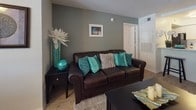 This single-floor residence offers a thoughtfully designed layout with multiple bedrooms, two full bathrooms, a dedicated dining area, a comfortable living room, and a functional kitchen — all connected by consistent light wood-style flooring throughout the main areas and plush carpet in the bedrooms.

The kitchen is efficiently arranged in a galley style, featuring white cabinetry with wood-tone trim, light countertops, and a full suite of black appliances including a refrigerator, electric range with overhead ventilation, and a separate sink area. The dining space adjoins the kitchen and benefits from a large window with vertical blinds that allows natural light and views of outdoor greenery, complemented by a ceiling fan overhead.

The living room features a textured ceiling, wood-style flooring, and a neutral-toned accent wall, creating a relaxed and welcoming atmosphere. The bedrooms are carpeted and generously sized — the primary bedroom includes a walk-in closet, while additional bedrooms offer standard closets with paneled doors. Each bathroom is finished with white vanities, large mirrors, wood-style flooring, and tub-shower combinations. A dedicated laundry room with side-by-side full-size washer and dryer hookups and a small window rounds out this practical and comfortable home.