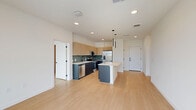 Located at 700 Hamilton Avenue in Nashville, TN, this modern 2-bedroom, 2-bathroom residence offers a well-designed single-floor layout with clean contemporary finishes throughout. Light hardwood flooring flows seamlessly across the entire space, complementing the crisp white walls and creating a bright, cohesive aesthetic.

The open-concept living area combines the dining room, kitchen, and living room into one connected space. The kitchen is a standout feature, boasting two-tone cabinetry with warm wood uppers and dark lower cabinets, a sage green tile backsplash, stainless steel appliances, a matte black faucet, and a central island with a quartz countertop and pendant lighting above. Floor-to-ceiling glass doors in the living area bring in abundant natural light and offer views of the Nashville skyline and surroundings.

Both bathrooms are finished with modern touches, including floating wood vanities with quartz countertops, matte black hardware, and bold black-tiled shower and tub surrounds. The primary bathroom features a walk-in glass shower alongside direct access to a dedicated walk-in closet. The second bedroom enjoys large picture windows overlooking the neighborhood. Additional conveniences include in-unit laundry, a utility room, and four closets throughout.