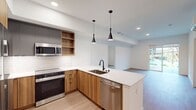 This contemporary apartment, located at 16771 Redmond Way in Redmond, WA, offers 920 square feet of efficiently designed living space. The single-floor layout comprises two bedrooms, including a primary bedroom of 160 square feet, one bathroom, and an open-concept kitchen and living area.

The heart of the home is the modern kitchen, featuring wooden cabinetry, stainless steel appliances, and a striking contrast of light and dark elements. A generously sized island with a built-in sink serves as both a functional workspace and a casual dining area. Pendant lighting adds a touch of elegance to the space.

The living room flows seamlessly from the kitchen, creating an ideal space for entertaining or relaxing. Large windows and sliding glass doors allow natural light to flood the area and provide access to an outdoor space, perfect for enjoying fresh air or urban views.

The bathroom showcases a clean, contemporary design with a glass-enclosed shower and neutral tiling. Two closets offer ample storage space, while the bedrooms provide comfortable retreats with continuation of the warm wood flooring found throughout the apartment.

Additional amenities include air conditioning for year-round comfort and in-unit laundry facilities. The apartment's neutral color palette and modern finishes create a blank canvas for personalization, making it an ideal home for those seeking a stylish and functional urban living space in Redmond.