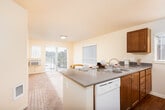 Located at 27431 172nd Ave SE in Covington, WA, this single-floor residence offers a well-designed, functional layout with a warm and inviting aesthetic throughout. The open-concept kitchen is a central highlight, featuring rich wood cabinetry, gray laminate countertops, a peninsula island with bar seating, and white appliances including a refrigerator, dishwasher, microwave, and range. Wood-style flooring runs through the kitchen and dining area, adding a touch of warmth and easy maintenance. Natural light filters in through multiple windows, including a sliding glass door that opens onto a private balcony, extending the living space outdoors.

The bedrooms are carpeted and offer a comfortable, quiet atmosphere. Each bedroom includes dedicated closet space equipped with wire shelving and hanging rods, providing practical storage solutions. The layout also reveals a separate walk-in style closet accessible from one of the bedroom areas.

Two bathrooms serve the residence, each finished with wood-style flooring, wood-toned vanity cabinetry, and light countertops. One bathroom includes a shower-tub combination, while the other functions as a half or full bath. Neutral wall tones throughout the home create a clean, move-in-ready canvas that complements a variety of interior styles.