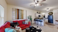 This one-bedroom, one-bathroom unit in Norman, Oklahoma offers a well-organized single-floor layout that makes efficient use of its compact footprint. The open-concept living and kitchen area serves as the heart of the space, where a ceiling fan with integrated lighting anchors the living room, which features carpet flooring and a window that brings in natural light. The kitchen is positioned adjacent to the living area and is separated by a breakfast bar with dark granite-style countertops and bar seating, making it both functional and social. The kitchen is equipped with black appliances, including a range, microwave, and refrigerator, complemented by white cabinetry extending to the ceiling for ample storage. Tile flooring runs through the kitchen and dining area, which also accommodates a small dining table. A hallway connects the main living space to the private areas of the unit, including the bedroom, bathroom, and a dedicated closet. The bedroom is a comfortable size, with carpeted flooring, a window allowing natural light, and enough space for standard furnishings. The bathroom features tile flooring, a vanity with under-sink cabinetry, a framed mirror, and wall-mounted lighting.