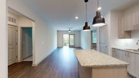 Located at 2190 Northlake Parkway in Tucker, GA, this well-appointed 2-bedroom, 2-bathroom unit offers a thoughtfully designed single-level layout. The open-concept kitchen and living area serves as the heart of the home, featuring rich wood-style flooring, recessed lighting, and stylish pendant lights. The kitchen is outfitted with light wood cabinetry, stainless steel appliances — including a refrigerator, range, microwave, and dishwasher — and a granite-topped island that doubles as a breakfast bar. The living area extends naturally toward a private balcony accessed through glass doors, filling the space with natural light and outdoor views. A ceiling fan adds comfort overhead. Both bedrooms offer plush carpeting, ceiling fans, and windows with blinds that invite natural light while maintaining privacy. The two bathrooms are finished with granite-topped vanities, wood-tone cabinetry, and wood-style flooring. One bathroom features a soaking tub and shower combination, while the other offers an elongated vanity with a large mirror, providing ample storage and functionality. Clean lines, neutral tones, and modern finishes throughout create a cohesive and contemporary living environment.