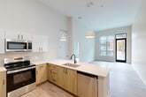 Located at 2111 Packard St in Ann Arbor, MI, this modern 2-bedroom, 2-bathroom unit is thoughtfully designed with contemporary finishes and an efficient single-floor layout. The open-concept living and dining area flows seamlessly into a well-appointed kitchen, which features a peninsula with a white quartz countertop, a dual-basin sink with a matte black faucet, stainless steel appliances including a refrigerator, electric range, built-in microwave, and dishwasher, along with two-tone cabinetry combining white upper cabinets and natural wood-toned lower cabinets. Striking pendant lights hang above the peninsula, and soaring ceilings enhance the sense of openness. Light wood-look flooring runs throughout the main living spaces, while plush carpeting adds comfort to the bedrooms. Large windows in the bedrooms invite natural light and offer views of the surrounding Ann Arbor neighborhood. The bathrooms are finished with clean, modern tile, glass-enclosed showers, white vanities with quartz countertops, matte black fixtures, and elegant vanity lighting. Three closets provide ample storage, and the unit also includes a dedicated laundry area and utility room for added convenience.