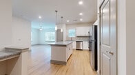 Located at 2272 Parkstone Dr in Indian Land, SC, this well-appointed one-bedroom, one-bathroom residence offers a thoughtfully designed open-concept layout across a single floor. Light hardwood flooring flows throughout the main living areas, creating a bright and cohesive atmosphere.

The kitchen serves as the centerpiece of the space, featuring crisp white shaker cabinetry, granite countertops, a subway tile backsplash, and a full suite of stainless steel appliances including a range, microwave, dishwasher, and refrigerator. A central island with pendant lighting above provides additional prep space and seating, opening seamlessly into the living area, which is accented by a ceiling fan and an exterior door leading to a private outdoor area.

The bedroom is a comfortable, well-sized retreat finished with plush wall-to-wall carpeting, a ceiling fan, and a window with blinds that invites natural light. An adjacent walk-in closet features wire shelving systems for organized storage.

The bathroom is finished with white cabinetry, granite countertops, a large vanity mirror, and hardwood-style flooring, maintaining the clean, modern aesthetic found throughout the home. Neutral wall tones and consistent trim details unify the space, lending it a polished, move-in-ready appeal.