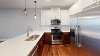 Located at 2800 Girard Ave S in the Uptown neighborhood of Minneapolis, Minnesota, this two-story residence offers a well-designed layout with quality finishes throughout. The main level showcases warm, rich hardwood flooring that flows through the open living area, which is anchored by large sliding glass doors that invite natural light and provide direct access to a lush outdoor green space. The kitchen is thoughtfully appointed with white upper cabinetry, dark wood lower cabinets, white quartz countertops, a tile backsplash, stainless steel appliances including a gas range and French door refrigerator, and stylish pendant lighting. A convenient half bathroom is also located on the main floor. A carpeted staircase with a wood handrail leads to the upper level, where the bedrooms are situated. Each bedroom features neutral carpet, ceiling fans, and windows that provide natural light and outdoor views. The bathrooms are well-finished with warm wood vanities, white quartz countertops, and tile flooring. Walk-in closets with built-in shelving are accessible from the bathrooms, offering generous storage. The overall aesthetic is clean and contemporary, with a neutral color palette and consistent, quality materials carried throughout both floors.