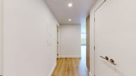 Located at 3551 Boulevard Gouin Est in Montréal, this thoughtfully designed one-bedroom, one-bathroom unit offers a clean, contemporary aesthetic throughout. Light wood laminate flooring runs seamlessly across the entire space, complementing the crisp white walls and modern finishes.

The open-concept kitchen and living area serves as the heart of the unit. The kitchen features a large island with a white quartz countertop, integrated sink, white cabinetry, a subway tile backsplash, warm wood accents, stainless steel appliances including a range and dishwasher, and a wall-mounted air conditioning unit. Recessed lighting adds a polished touch overhead.

The living area is bathed in natural light through expansive floor-to-ceiling windows fitted with black frames, offering sweeping views of the Montréal cityscape and surrounding greenery. A door provides access to a balcony, further extending the connection to the outdoors.

The bedroom is a bright, well-proportioned retreat with its own large window framing outdoor views and a closet for ample storage. The bathroom is finished with large-format white tiles, a glass-enclosed walk-in shower, wood-toned cabinetry, and modern fixtures. A dedicated laundry area and hallway complete this efficiently laid-out home.