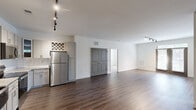 Located in Wake Forest, NC, this well-appointed two-bedroom, two-bathroom residence offers a thoughtfully designed single-level layout. The open-concept living, dining, and kitchen area serves as the heart of the home, finished with rich hardwood-style flooring and track lighting throughout. The kitchen is equipped with stainless steel appliances — including a refrigerator, range, microwave, and dishwasher — complemented by gray shaker-style cabinetry, a white subway tile backsplash, and granite-look countertops, creating a clean and modern aesthetic.

The spacious primary bedroom features plush carpeting, a ceiling fan, and access to a well-organized walk-in closet with wire shelving. The en-suite bathroom offers a glass-enclosed walk-in shower, granite vanity, LED-lit mirror, and gray cabinetry. The second bedroom is equally comfortable with soft carpet and a ceiling fan. The second bathroom features a tub/shower combination with tiled surround and wood-style flooring.

Additional highlights include a dedicated office space with French doors that open to the balcony, flooding the room with natural light. Three closets, an in-unit laundry room, and stylish gray interior doors with panel detailing round out this functional and attractive residence.