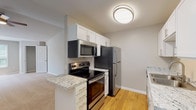 Located at 1140 Trinity Pines Ln in Raleigh, NC, this single-floor residence offers a well-designed layout with thoughtfully updated interiors throughout. The kitchen is a standout feature, showcasing white shaker-style cabinetry, granite countertops, a stainless steel sink, and a full suite of stainless steel appliances including a refrigerator, electric range, and over-the-range microwave. Warm hardwood flooring runs through the kitchen and connects seamlessly to the main living areas. The open living area is spacious and bright, with vaulted ceilings, neutral carpet, and direct sightlines to the kitchen, creating an open and airy feel. A front entry door with a keypad adds a layer of convenience and security. The bedrooms are generously sized, each featuring plush carpet, neutral paint tones, and ample closet space — including a walk-in closet in one of the rooms. Natural light flows in through large windows, with greenery visible from the primary bedroom. The bathrooms are finished with granite-top white vanities, hardwood flooring, and a tub-shower combination, maintaining a clean and consistent aesthetic. Overall, the space presents a move-in ready interior with modern finishes in a comfortable Raleigh setting.