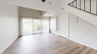 Located at 511 Payne Hill Rd in Jefferson Hills, PA, this two-story, one-bedroom, one-bathroom unit offers an efficient and well-designed layout spread across two floors. The main level features an open-concept living room and kitchen combination with light hardwood-style flooring throughout. The living area benefits from vaulted ceilings and large sliding glass doors that flood the space with natural light and provide views of the surrounding greenery. A ceiling fan adds comfort to the airy living space. The kitchen is appointed with rich dark cabinetry, granite countertops, a stainless steel sink, and stainless steel appliances, including a range and dishwasher, all visible through a convenient pass-through opening to the living area. A carpeted staircase leads to the upper floor, where the spacious bedroom features soft carpet, an open railing overlooking the lower level, and a window with outdoor views. The full bathroom is finished with a tiled tub-and-shower combination, a dark-cabinetry vanity with a white countertop, and light hardwood-style flooring. A dedicated laundry area with a stacked washer and dryer unit, along with a utility room, adds everyday practicality. The space is clean, bright, and move-in ready throughout.