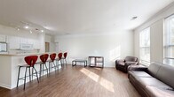 Located at 4197 Harding Hwy in Lima, Ohio, this single-floor unit offers a well-organized layout designed for comfortable, functional living. The open-concept living and dining area is one of the space's most notable features, showcasing light wood-style flooring, crisp white walls accented with crown molding, and generous windows that flood the room with natural light. A breakfast bar with bar-height seating connects the living area to the kitchen, which is equipped with white cabinetry, a refrigerator, electric range, and over-the-range microwave, providing ample storage and prep space.

The bedrooms feature plush carpeting and windows that bring in natural light, with one room accommodating multiple beds and furnishings, making it suitable for shared occupancy. A spacious walk-in closet outfitted with wire shelving and multiple coat hooks offers substantial storage capacity. The bathroom is well-appointed with a dual-sink vanity, warm-toned countertops, tile flooring, and a large mirror. A dedicated laundry room houses a full-sized washer and dryer alongside a water heater, adding everyday convenience. Overall, the space presents a clean, neutral palette with a practical and welcoming ambiance.