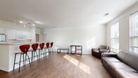 Located at 4197 Harding Hwy in Lima, Ohio, this single-floor unit offers a well-organized layout designed for comfortable, functional living. The open-concept living and dining area is one of the space's most notable features, showcasing light wood-style flooring, crisp white walls accented with crown molding, and generous windows that flood the room with natural light. A breakfast bar with bar-height seating connects the living area to the kitchen, which is equipped with white cabinetry, a refrigerator, electric range, and over-the-range microwave, providing ample storage and prep space.

The bedrooms feature plush carpeting and windows that bring in natural light, with one room accommodating multiple beds and furnishings, making it suitable for shared occupancy. A spacious walk-in closet outfitted with wire shelving and multiple coat hooks offers substantial storage capacity. The bathroom is well-appointed with a dual-sink vanity, warm-toned countertops, tile flooring, and a large mirror. A dedicated laundry room houses a full-sized washer and dryer alongside a water heater, adding everyday convenience. Overall, the space presents a clean, neutral palette with a practical and welcoming ambiance.