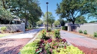 Located at 2225 Ashley River Road in Charleston, South Carolina, this single-story property is set within a thoughtfully maintained residential community that exudes classic Lowcountry charm. The approach to the space immediately impresses with a grand, tree-lined boulevard framed by mature oaks and lush canopy coverage that provides natural shade throughout the grounds. A central landscaped median bursts with colorful seasonal plantings — including vibrant impatiens, ornamental grasses, and tropical foliage — flanked by brick-accented pathways that invite leisurely strolls. Classic black lamp posts line the thoroughfare, adding a timeless, elegant character to the streetscape. The surrounding grounds are well-manicured, with verdant lawns and carefully tended shrubbery contributing to an atmosphere of tranquility and order. The community's architecture complements the natural setting, with structures that blend harmoniously into the tree-filled landscape. The overall ambiance is one of peaceful, park-like living, characteristic of Charleston's West Ashley corridor — offering residents a serene environment with a strong sense of place and community, all within easy reach of the city's rich cultural and historical offerings.
