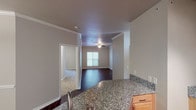 This single-floor residence is thoughtfully designed with a cohesive blend of finishes and functional layout. The kitchen serves as a central highlight, featuring granite countertops, light wood cabinetry, stainless steel appliances including a range, built-in microwave, and refrigerator, all complemented by dark hardwood flooring and track lighting overhead. A breakfast bar with an undermount sink extends the counter space and connects the kitchen to the adjoining living area.

The living area continues the dark hardwood flooring and is accented with crown molding and a ceiling fan, with a window providing natural light. Multiple bedrooms are finished with neutral-toned carpet and windows fitted with slatted blinds, offering a quiet, comfortable atmosphere. One bedroom includes a sliding closet door, adding practical storage.

The bathrooms are well-equipped, with the primary bathroom featuring granite countertops, a single undermount sink, light wood vanity cabinetry, a soaking tub, and a separate shower area, brightened by a window. The secondary bathroom offers a tiled tub-shower combination with clean, functional fixtures. Dark hardwood flooring runs through both bathrooms, maintaining a consistent aesthetic throughout the home.
