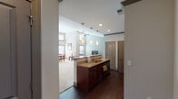 This thoughtfully designed single-floor residence offers a seamless blend of comfort and functionality across its well-organized layout. The open-concept living and dining area is a standout feature, boasting dramatically high ceilings lined with a double row of windows that flood the space with abundant natural light. Soft carpeting and neutral tones throughout create a warm, welcoming ambiance.

The kitchen is both stylish and practical, featuring rich dark wood cabinetry, granite countertops, stainless steel appliances including a refrigerator, range, and built-in microwave, and a peninsula island with an undermount sink. Dark hardwood flooring anchors the kitchen and flows into the adjoining hallway. Pendant lighting above the island adds a refined touch.

Two comfortable bedrooms provide restful retreats, each with plush carpeting and soft neutral walls. The primary bedroom includes a ceiling fan, while the secondary bedroom offers a cozy, quiet atmosphere. Both bathrooms are finished with granite-topped vanities, warm wood cabinetry, and tile flooring. One bathroom features a full tub-shower combination, while the second serves as a convenient three-quarter bath.

A dedicated in-unit laundry room houses a full-sized washer and dryer with overhead wire shelving, adding everyday practicality to this well-rounded residence.