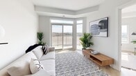 Located at 80-100 Starwood Dr in Guelph, Ontario, this well-appointed one-bedroom, two-bathroom unit offers a thoughtfully designed open-concept layout finished with light hardwood flooring and crisp white walls throughout. The kitchen is a standout feature, showcasing two-tone cabinetry with white upper cabinets and warm walnut-finish lower cabinets, stainless steel appliances, under-cabinet lighting, and a generous island with a quartz countertop and bar seating — ideal for both everyday living and entertaining. The kitchen flows seamlessly into the bright living area, which is anchored by large sliding glass doors leading to a private balcony with expansive views of the surrounding landscape. A dedicated office space with a large window provides an abundance of natural light and scenic outdoor views, making it a productive and comfortable workspace. The primary bedroom is a serene retreat, featuring a window with views of the neighbourhood and ample natural light. Two well-appointed bathrooms complete the unit: one featuring a glass-enclosed walk-in shower with subway tile surround and brushed nickel fixtures, and the other offering a full soaker tub with matching tile work. A closet, hallway, and additional rooms round out this functional and stylish home.
