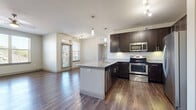 Located at 200 Philomena Dr in Kyle, TX, this one-bedroom, one-bathroom residence offers a well-designed, single-floor layout with a thoughtful blend of modern finishes and functional spaces. The open-concept living area seamlessly connects the kitchen, dining, and living room, creating an airy and cohesive environment. Rich hardwood-style flooring flows throughout the main living areas, complemented by neutral-toned walls that enhance the sense of brightness and space.

The kitchen is a standout feature, centered around a granite-topped island with a built-in sink and pendant lighting overhead. Dark espresso cabinetry provides ample storage, while a full suite of stainless steel appliances—including a refrigerator, range, microwave, and dishwasher—adds a sleek, contemporary touch. A dedicated pantry offers additional storage convenience. Large windows in the living area allow natural light to pour in, with views of the surrounding neighborhood.

The bedroom is carpeted for comfort and includes a ceiling fan, a window with outdoor views, and access to a spacious walk-in closet with wire shelving. The bathroom features a double-sink vanity with granite countertops, dark cabinetry, and hardwood-style flooring. Additional highlights include a private balcony, in-unit laundry, and a second closet for extra storage.