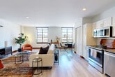Located along the coveted Ocean Boulevard corridor in Long Beach, California, this well-appointed one-bedroom, one-bathroom residence offers a thoughtfully designed open-concept layout. Light wood flooring flows seamlessly throughout, lending warmth and continuity to every room.

The combined kitchen and living area forms the heart of the home. The kitchen is outfitted with crisp white shaker cabinetry, a classic subway tile backsplash, dark countertops, and a full suite of stainless steel appliances, including a range, microwave, dishwasher, and refrigerator. A dining area connects naturally to the living space, which is generously proportioned and filled with natural light from a row of wide windows. A wall-mounted mini-split system provides efficient climate control, while a stylish barn door adds architectural character.

The bedroom offers a serene retreat, highlighted by a bold botanical-print accent wall that adds a lively, artistic focal point. A sliding closet and recessed lighting complete the space. The hallway connecting the rooms is clean and well-lit, reinforcing the home's open and airy feel.

The bathroom features full subway tile surround, a soaking tub with shower, terrazzo-style flooring, and a white vanity with dark countertop. Every detail reflects a cohesive, modern aesthetic throughout this vibrant Long Beach residence.