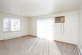 This single-floor residence offers a practical and comfortable layout designed for everyday living. The kitchen is a standout feature, equipped with warm honey-toned wood cabinetry extending to the ceiling for ample storage, light countertops, stone-look tile flooring, and a full suite of appliances including a black refrigerator, electric range with overhead microwave, and dishwasher. A pass-through counter connects the kitchen to the living area, enhancing the open feel of the space.

The living area is generously sized, finished with neutral wall-to-wall carpeting and baseboard heating, and receives natural light through exterior-facing windows. Multiple bedrooms continue the carpeted flooring theme, each featuring windows that bring in outdoor views of surrounding trees. The bedrooms are also equipped with ceiling fans, baseboard heaters, and wall-mounted air conditioning units for year-round comfort. One bedroom includes a sliding-door closet for convenient storage.

Two bathrooms serve the unit, both finished with earthy stone-look ceramic tile floors. One bathroom features a full tub-shower combination with clean white surrounds, while the other includes additional storage space. Textured ceilings are present throughout, adding a consistent design element across the home.