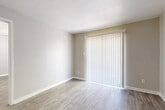 This efficiently laid-out single-story unit offers a cohesive and clean aesthetic throughout its thoughtfully organized floor plan. Warm-toned, light wood-style flooring runs continuously through every room, creating a unified and easy-to-maintain interior.

The combined living and dining area serves as the heart of the unit, bathed in natural light through large sliding glass doors dressed with vertical blinds, lending an open and airy feel to the space. A front entry door opens directly into this living area, providing a welcoming point of arrival.

The kitchen features dark espresso cabinetry paired with light marbled countertops, a stainless steel double-basin sink, and black appliances including a refrigerator and range. The galley-style layout maximizes efficiency within a compact footprint.

The bedroom is a comfortable, well-proportioned room equipped with a ceiling fan, a window with horizontal blinds for natural light and privacy, and access to two closets — including a walk-in closet outfitted with multiple hanging rods and built-in shelving for generous storage.

The bathroom offers a clean, functional design with a full tub-shower combination, a dark-framed vanity with a light countertop, and matching wood-style flooring. Neutral wall tones throughout the unit contribute to a calm, move-in ready atmosphere.