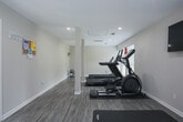 Located at 1001 N Donahue Dr in Auburn, Alabama, this fitness center is a well-equipped, single-floor facility designed to support a comprehensive workout routine. The space features durable wood-look flooring throughout, neutral-toned walls, and multiple windows fitted with blinds that allow natural light to fill the room while maintaining privacy with views of the surrounding greenery outdoors.

The cardio area is outfitted with multiple treadmills, an elliptical trainer, and a rowing machine, all positioned along the perimeter to maximize open floor space. Equipment mats are placed beneath each machine for stability and floor protection. A wall-mounted flat-screen TV is conveniently positioned for entertainment during workouts.

The strength and functional training area features a Hoist cable machine, a dumbbell rack with a full set of free weights, stability balls, and exercise mats for stretching or floor work. A fitness reference chart is posted on the wall for guidance. The space also includes structural columns that subtly divide workout zones without disrupting the open feel of the facility.

A clearly marked exit door with a full-length glass panel leads to an outdoor area, and a community bulletin board near the entrance keeps users informed. The overall ambiance is clean, functional, and well-maintained, making it a practical and welcoming fitness amenity.