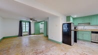 Located in Houston's vibrant Montrose neighborhood, this single-floor property at 709 Avondale St offers a distinctive retro character defined by its consistent mint-green color palette throughout. The interior features open living areas with raw, weathered concrete floors that lend an industrial charm, while white walls trimmed in mint-green baseboards and door frames tie the aesthetic together cohesively.

The main living area is generously proportioned, equipped with a ceiling fan and windows dressed with dark curtains, allowing for flexible light control. A set of built-in green shelving units flanks a central green paneled door, providing ample display and storage space. A stained glass window accent adds a touch of classic craftsmanship to the room.

The kitchen is compact yet functional, featuring mint-green cabinetry, a butcher block countertop, a stainless steel electric range, a refrigerator, and a utility sink — offering a retro-meets-modern cooking space.

The bathroom is a standout feature, showcasing a classic clawfoot bathtub set against walls finished in painted horizontal shiplap boards in a soft sage green, evoking a timeless, vintage aesthetic. A wall-mounted window AC unit provides climate control throughout the space. This property presents strong character and renovation potential in a sought-after Houston location.