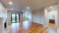 This thoughtfully designed single-floor residence combines modern finishes with functional living spaces. Rich hardwood flooring flows throughout the main areas, lending warmth and continuity to the open layout.

The expansive living area is a standout feature, bathed in natural light from large windows and sliding glass doors that open onto a balcony with scenic outdoor views. The open, airy feel is enhanced by recessed lighting and clean, neutral-toned walls.

The kitchen is well-equipped for culinary use, showcasing rich dark wood cabinetry extending to the ceiling for ample storage, light quartz countertops, and a full suite of stainless steel appliances including a gas range, built-in microwave, side-by-side refrigerator with ice and water dispenser, and dishwasher. A kitchen island provides additional prep and counter space.

The bedroom offers a peaceful retreat with dual windows framing treetop views, hardwood flooring, and access to a well-organized walk-in closet with wire shelving and hanging rods.

Two bathrooms serve the residence, each finished with quartz countertops, wood-toned cabinetry, and brushed nickel fixtures. The primary bathroom features a large vanity mirror and grab bars, while the second includes a full tub and shower combination. The overall ambiance is clean, modern, and move-in ready.