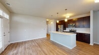 This single-floor residence in Romeoville, IL offers a thoughtfully designed open-concept layout that seamlessly connects the kitchen, dining, and living areas. The kitchen is a standout feature, showcasing rich dark-brown cabinetry, crisp white countertops, and a full suite of stainless steel appliances including a refrigerator, electric range, and over-the-range microwave. A central kitchen island with an integrated sink and elegant pendant lighting serves as both a functional workspace and a natural gathering point, anchoring the living space with style.

The open living and dining area is finished with warm, light-toned wood-style flooring that extends throughout, creating a cohesive and inviting atmosphere. Large windows allow natural light to fill the space, offering views of the surrounding neighborhood. The bedroom is carpeted for comfort, with a generous window that continues the theme of natural light.

The bathroom is clean and efficiently laid out, featuring wood-style flooring consistent with the rest of the home, a dark-vanity with a sink, a toilet, and a shower area with chrome grab bar hardware. Neutral wall tones throughout the residence create a versatile backdrop, while the overall design balances modern aesthetics with everyday practicality, making this Romeoville home a comfortable and move-in-ready living space.