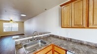 This three-story home offers four bedrooms, three bathrooms, and a well-organized layout spread across three distinct levels. The ground floor houses an attached garage with a concrete floor, automatic opener, and direct interior access, providing practical convenience alongside additional storage potential.

The main level features a combined kitchen and living room that forms the heart of the home. The kitchen is equipped with warm honey-toned wood cabinetry, granite-style laminate countertops, a stainless steel sink, and white appliances including a range, built-in microwave, and dishwasher. Light tile flooring carries through the kitchen, while durable hardwood-style flooring extends into the open living area. Carpeted staircases connect all three levels, supported by multiple hallways that ensure smooth circulation throughout.

The upper floor contains the bedrooms, including a spacious primary bedroom. Bedrooms feature plush carpeting or hardwood-style flooring, ceiling fans with integrated lighting, and windows that invite natural light and neighborhood views. The three bathrooms are finished with tile flooring, wood vanity cabinetry, and tub-shower combinations with chrome fixtures. A dedicated closet adds further storage. Neutral tones and clean white trim are consistent throughout, creating a cohesive and functional living environment.