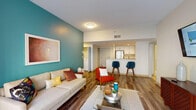 Located at 500 Broadway in Malden, MA, this well-appointed single-floor residence offers a thoughtfully designed open-concept layout. The living area is anchored by rich hardwood-style flooring and a bold teal accent wall, creating a vibrant yet inviting atmosphere. Large sliding glass doors flood the space with natural light and provide access to an outdoor area, enhancing the sense of openness. The kitchen features crisp white shaker cabinetry, granite countertops, stainless steel appliances—including a refrigerator, range, and microwave—and a breakfast bar with seating, seamlessly connecting to the living space. The bedrooms offer plush carpeting, neutral tones, and distinct accent walls in navy and slate blue, each providing a calm retreat with ample closet storage. The bathrooms are finished with white cabinetry, granite-topped vanities, large mirrors, and tile flooring; one includes a full soaking tub with shower, while another offers an elongated vanity with generous storage. A dedicated laundry area adds everyday convenience. Throughout the residence, a cohesive mid-century modern aesthetic ties together bold color accents, contemporary finishes, and functional design.