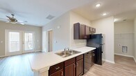 Located at 801 Booth Rd in Warner Robins, Georgia, this single-floor 1-bedroom, 1-bathroom residence offers a thoughtfully designed layout that maximizes functionality and comfort. The kitchen is a standout feature, equipped with rich dark espresso cabinetry, white countertops, black appliances including a refrigerator, electric range, and built-in microwave, along with a peninsula with a double-basin sink that opens toward the living area. Recessed lighting and a chandelier accent add to the kitchen's polished look. The living room is bright and airy, featuring light wood-look vinyl flooring, a ceiling fan, and French doors that open to an outdoor area, allowing natural light to fill the space. The bedroom offers plush carpeting, dual windows with blinds, a ceiling fan, and a walk-in closet with wire shelving for ample storage. The bathroom is clean and functional, featuring a dark-cabinet vanity with a white countertop, a well-lit mirror, and a full soaking tub with shower and grab bar. Light wood-look flooring runs through the bathroom, complementing the neutral warm tones found throughout the entire residence. The overall aesthetic is modern, clean, and move-in ready.