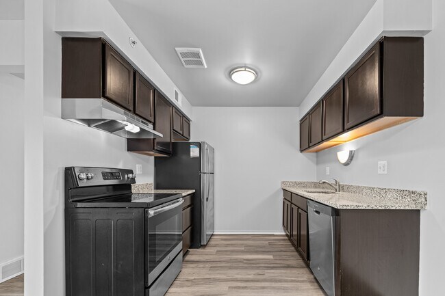 Cocina renovada con electrodomésticos de acero inoxidable y encimeras de granito en Westwood Village Apartments en Westland, MI - Westwood Village Apartments