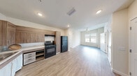 Located at 1250 NW 36th St in Miami, FL, this 2-bedroom, 2-bathroom residence offers a well-designed, single-floor layout. The open-concept living, dining, and kitchen area creates a spacious, connected feel, anchored by light wood-look flooring that runs throughout. The kitchen is outfitted with warm wood-tone cabinetry, open shelving, black appliances including a gas range and refrigerator, and a dishwasher — all designed for both function and style. A ceiling fan in the living area enhances comfort, while natural light flows in through windows overlooking the surrounding neighborhood. Each bedroom features tray ceilings, large windows with blinds, and hardwood-style flooring, creating a bright and airy atmosphere. The primary bedroom includes direct access to a closet and a full bathroom. Both bathrooms are equipped with accessibility features including grab bars, with one offering a walk-in shower and the other a bathtub. The closets feature built-in wire shelving systems, maximizing storage. Additional spaces include a dedicated laundry room and a utility room. The unit also benefits from in-unit storage and an accessible, thoughtfully laid-out floor plan suited for a range of lifestyles.