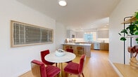 This thoughtfully designed three-floor residence offers 3 bedrooms, 3 bathrooms, a dedicated office, and a seamless open-plan kitchen and dining area, providing a functional and comfortable layout across its three levels. The entry level serves as a compact but practical base, while the main living floor serves as the heart of the home. Here, the open-concept kitchen and dining room flow naturally together, featuring two-tone cabinetry with warm wood lower cabinets and light grey uppers, white quartz countertops, stainless steel appliances, a subway tile backsplash, and a peninsula with bar seating. The adjacent dining area accommodates a round marble-top table, and the bright living room benefits from a large picture window framing outdoor views and flooding the space with natural light. Light hardwood flooring runs throughout the main level, lending warmth and continuity. The upper floor houses the bedrooms, including a well-proportioned primary suite with a walk-in closet, en-suite bathroom, and a large sliding window overlooking the neighborhood. Additional bedrooms are similarly bright and carpeted. A dedicated office with ample natural light and built-in desk space completes the upper level. Clean white walls, recessed lighting, and a consistent modern aesthetic tie the entire home together with a fresh, contemporary feel.