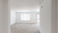 This single-floor residence offers a functional and comfortable layout spanning a generous footprint, featuring 2 bedrooms, 3 bathrooms, and a well-organized arrangement of living spaces. The unit is accessed through a dedicated entrance that leads into a hallway connecting the key areas of the home.

The open living room is bright and airy, finished with plush carpeting and white walls that maximize the natural light streaming through large windows fitted with horizontal blinds. A sliding glass door provides direct access to an outdoor area, enhancing the sense of openness. The adjacent kitchen is well-equipped with light wood-tone cabinetry, white quartz-style countertops, a white subway tile backsplash, wood-look flooring, and a full suite of stainless steel appliances including a range, refrigerator, and dishwasher. A pass-through connects the kitchen to the living area.

Both bedrooms feature soft carpeting and built-in closets with wire shelving systems. The spacious primary bedroom includes its own dedicated bathroom. The three bathrooms are finished with wood-look tile flooring and light cabinetry; one features a walk-in shower with a sliding glass door and grab bars. A utility room and three closets provide additional storage throughout.