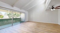 Located at 2130 W Crescent Ave in Anaheim, CA, this 2-bedroom, 1-bathroom single-story home offers a thoughtfully designed layout with attractive architectural details throughout. The standout feature is the vaulted ceiling with exposed white-painted wood beams, visible in the primary living areas, which creates an airy, open atmosphere. Light wood flooring runs consistently throughout the home, complementing the neutral, warm-toned walls.

The spacious primary bedroom features the vaulted beamed ceiling, a ceiling fan, and a sliding glass door opening to a private balcony with views of surrounding mature trees — an inviting outdoor extension of the living space. The second bedroom is well-proportioned, featuring mirrored sliding closet doors and vertical blinds that filter abundant natural light. Both bedrooms offer a calm, bright ambiance.

The kitchen is efficiently appointed with white cabinetry, a dishwasher, and a sink, alongside a dedicated walk-in pantry for generous storage. The bathroom features a full tub and shower combination with clean white finishes. The living room showcases the same vaulted ceiling and beamed detail, adding character and openness to the shared living area. Overall, the home presents a clean, move-in ready aesthetic throughout.