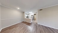 Located at 8585 Spicewood Springs Rd in Austin, TX, this single-floor, three-bedroom, one-bathroom unit offers a well-designed layout with a comfortable mix of flooring and functional living spaces. The open-concept kitchen and living area serves as the heart of the home, featuring wood-look laminate flooring, crown molding, and a ceiling fan with direct access to an outdoor area via sliding glass doors framed by vertical blinds that invite natural light. The kitchen is outfitted with white shaker-style cabinetry, light countertops, a peninsula with a sink, and a full suite of stainless steel appliances including a refrigerator, range, microwave, and dishwasher. The three bedrooms offer a mix of carpet and wood-look flooring, each with neutral-toned walls and ceiling fans for comfort. The spacious primary bedroom connects to a walk-in closet with wire shelving for organized storage. The bathroom features a wide vanity with white cabinetry and a large mirror, a tub-shower combination, and wood-look tile flooring. A dedicated hallway connects all rooms, completing this practical and well-appointed layout.