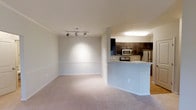 Located at 1431 W Nine Mile Rd in Pensacola, Florida, this single-floor residence offers a clean, open-concept layout designed for comfortable everyday living. The living area is generously proportioned, featuring plush wall-to-wall carpeting and a modern track lighting fixture on the ceiling that allows for flexible, directed illumination throughout the space. Neutral-toned walls and white trim contribute to a bright, airy atmosphere.

The kitchen is separated from the living area by a raised peninsula counter, creating a natural division while maintaining an open feel. Dark espresso-toned cabinetry provides a bold contrast against the light countertops and walls, offering ample storage space. Stainless steel appliances — including a refrigerator, microwave, and range — lend a contemporary, functional edge to the kitchen. The hard surface flooring in the kitchen area complements the carpeted living space seamlessly.

The overall design of the unit is cohesive and modern, with consistent finishes throughout. The open flow between the kitchen and living areas makes the space feel expansive and well-connected, ideal for both daily routines and casual entertaining. The thoughtful layout and updated interior finishes make this a well-appointed single-level residence in Pensacola.