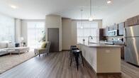 Located at 7600 Terrace Ave in Middleton, Wisconsin, this thoughtfully designed single-floor residence offers a seamless blend of modern finishes and functional living. The open-concept living and kitchen area is anchored by rich hardwood-style flooring and soaring ceilings that amplify the sense of space. Large windows dressed with horizontal blinds bathe the living area in natural light, while a generously sized sectional seating area invites relaxation with views to the outdoors.

The kitchen is a standout feature, equipped with stainless steel appliances, rich dark-toned cabinetry, granite countertops, and a peninsula with bar seating illuminated by pendant lighting — ideal for both casual dining and entertaining. The bedrooms offer plush carpeting, ample natural light, and walk-in closet storage. The bathroom is finished with granite-topped dark wood vanity cabinetry, a large mirror, and hardwood-style flooring, complemented by a second half-bath for added convenience.

A dedicated in-unit laundry room houses a full-size front-loading washer and dryer with additional shelving storage. Throughout the space, neutral tones, clean lines, and quality finishes create a cohesive, contemporary aesthetic well-suited for comfortable everyday living.