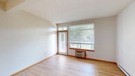 Located at 9310 N Camden Ln in Spokane, WA, this one-bedroom, one-bathroom unit offers a thoughtfully designed single-floor layout that maximizes functionality and comfort. Light hardwood flooring flows throughout the main living areas, lending warmth and continuity to the open-concept living room, dining area, and kitchen. The living room is bright and airy, featuring a private entry door flanked by large windows with wood-trimmed accents that frame lush, mature tree views. A wall-unit air conditioner and baseboard heating provide year-round climate control.

The kitchen is defined by warm oak cabinetry, tile backsplash, recessed lighting, and a peninsula countertop that seamlessly connects to the dining and living spaces. White appliances, including a refrigerator, range, and over-the-range microwave, complete the functional setup.

The spacious bedroom is carpeted for comfort and includes a window overlooking greenery, a dedicated closet, and baseboard heating. The full bathroom features oak vanity cabinetry, a large mirror, tile surround tub-shower combo, and hardwood-style flooring.

A hallway connects all rooms efficiently, and the private balcony with glass railing offers a serene, tree-canopied outdoor retreat — a standout feature of this well-organized Spokane residence.