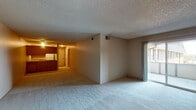 Located at 2770 E Uintah St in Colorado Springs, Colorado, this single-floor unit offers a practical and straightforward layout well-suited for comfortable everyday living. The open living and dining area is finished with plush carpeting and features a textured ceiling throughout. A sliding glass door floods the space with natural light and provides direct access to a private balcony, offering views of the surrounding exterior. The kitchen is equipped with warm wood-toned cabinetry, laminate countertops, a stainless steel sink, and a dishwasher, providing ample storage and workspace. A hallway connects the main living area to the rest of the unit, leading to the bedrooms and bathroom. The bedrooms are carpeted and lit by overhead fixtures, with windows allowing in natural light. One bedroom features a built-in shelf detail along the upper wall, adding a subtle architectural element. The bathroom includes a full tub and shower combination with clean white tile surround and chrome fixtures, along with tile flooring. Neutral wall tones and consistent textured ceilings run throughout the unit, creating a cohesive and understated aesthetic suited to a variety of personal styles.