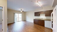 This single-floor, 1-bedroom, 1-bathroom unit offers a functional and efficient layout across a compact but well-utilized footprint. The open-concept living and kitchen area forms the heart of the unit, featuring rich hardwood-style flooring, neutral beige walls, and a ceiling fan with overhead track lighting. A sliding glass door floods the living space with natural light and provides direct access to a private balcony with exterior views.

The kitchen is equipped with dark espresso-toned cabinetry, granite-look countertops, a stainless steel sink, and white appliances including a refrigerator, electric range, microwave, and dishwasher. Track lighting above the kitchen workspace ensures excellent task illumination.

The bedroom offers plush carpeting, a ceiling fan, a natural light window, and a sliding-door closet with a built-in hanging rod. The hallway connects the main living spaces efficiently and includes access to additional storage.

The bathroom features a full tub-shower combination, a granite-topped vanity with dark cabinetry, hardwood-style flooring, and a notable convenience — a stacked in-unit washer and dryer. Warm, neutral tones throughout the unit create a cohesive and inviting atmosphere.