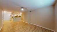 This single-floor residence offers a clean, modern aesthetic throughout, with light wood-style flooring and warm neutral tones creating a cohesive and inviting atmosphere across all rooms. The open living area connects seamlessly to the kitchen via a half-wall pass-through, enhancing the sense of openness. A ceiling fan with integrated lighting anchors the living space, which benefits from recessed lighting that adds a bright, polished feel.

The kitchen is a standout feature, outfitted with crisp white cabinetry, granite countertops, a mosaic tile backsplash, and a full suite of stainless steel appliances including a range, microwave, dishwasher, and refrigerator. A built-in wine cooler and open shelving add both functionality and character. Recessed lighting and a window above the sink keep the space well-lit.

The bedrooms are comfortably sized, each featuring the same wood-style flooring, ceiling fans or flush-mount lighting, and window treatments including blinds and vertical panel shades that allow for natural light control.

The bathroom is thoughtfully finished with a granite-topped vanity, white cabinetry, and a tub-shower combination surrounded by large-format travertine-style tiles accented by a decorative mosaic border strip, lending a spa-like quality to the space.