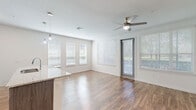 Located at 10387 Vista Oaks Ct in Orlando, FL, this well-appointed 2-bedroom, 2-bathroom single-story home offers a thoughtfully designed layout with modern finishes throughout. The open-concept kitchen and living area serves as the heart of the home, featuring wood-look plank flooring, a ceiling fan, and an abundance of natural light from multiple large windows. The kitchen stands out with a granite-topped center island with an undermount sink, sleek dark wood cabinetry, a white subway tile backsplash, stainless steel appliances, and elegant pendant lighting. The living area opens directly to a private patio through a glass door, extending the living space outdoors. Both bedrooms offer plush carpeting, ceiling fans, and ample natural light. The spacious primary bedroom includes a walk-in closet and a well-appointed en-suite bathroom with dual granite-topped vanities, illuminated mirrors, wood-tone cabinetry, and a glass-enclosed shower. A dedicated laundry room with an in-unit washer adds everyday convenience. A central hallway with wood-look flooring and recessed lighting connects all areas of the home seamlessly, complemented by clean white walls and consistent modern detailing throughout.