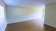 This two-floor property offers a clean and functional layout designed to maximize livable space. The main living area is notably spacious, featuring warm hardwood-style flooring that runs throughout and contributes to a welcoming, cohesive aesthetic. Light yellow-toned walls reflect natural light effectively, creating a bright and airy atmosphere. The textured ceiling adds a classic architectural touch consistent across the interior. The open layout of the main floor allows for versatile furniture arrangements and a sense of generous square footage. White baseboards provide a crisp contrast against the flooring, adding a tidy, finished look to the rooms. The overall design is straightforward and practical, prioritizing open space and ease of movement between areas. The second floor expands the property's functionality, offering additional room configurations suited for various uses. With its neutral color palette and durable finishes, this space provides a solid foundation that is move-in ready and easily adaptable to a range of interior styles and personal preferences. The combination of light walls, warm flooring, and consistent detailing throughout gives the property a unified and well-maintained character.
