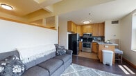 Located in the heart of downtown Madison, Wisconsin, this single-floor unit at 117 N Franklin St offers a functional and well-appointed layout. The open-concept living and kitchen area forms the core of the space, where dark hardwood-style flooring flows throughout, creating a cohesive and warm aesthetic. The living area accommodates comfortable seating and is anchored by a plush area rug, providing a welcoming atmosphere.

The kitchen is efficiently designed with warm oak cabinetry offering ample storage, granite-style countertops, a tile backsplash, and a full suite of stainless steel appliances including a refrigerator, range, over-the-range microwave, and dishwasher. Light tile flooring in the kitchen complements the overall design.

A separate room bathed in natural light from multiple large windows offers views of the surrounding Madison cityscape and greenery, making it a bright and versatile space. The bathroom features neutral tile flooring, dark espresso-finish cabinetry with granite-style countertops, and clean, simple finishes throughout.

The unit's location in downtown Madison places it within close proximity to local amenities, dining, and the broader urban core, making it a practical and comfortable urban living space.