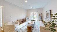 Located at 173 Monadnock Highway in Swanzey, New Hampshire, this thoughtfully designed two-bedroom, two-bathroom residence offers comfortable single-floor living. The open-concept kitchen is a standout feature, boasting a two-tone cabinetry scheme with white upper cabinets and warm wood lower cabinets, stainless steel appliances, quartz countertops, a central island with bar seating, and pendant lighting over light hardwood flooring. The kitchen flows seamlessly into the combined living and dining area, where a sliding glass door fills the space with natural light and provides access to an outdoor patio with views of surrounding greenery. The primary bedroom offers a serene retreat with plush carpeting, a window with natural light, and ample space for a four-poster bed. The second bedroom is equally well-lit, featuring a large window and carpeted flooring well-suited for a sitting area or home office. Both bathrooms are finished with tile flooring and warm wood cabinetry with matte black hardware. The full hall bathroom includes a soaking tub, while the second bathroom features a walk-in shower. Additional spaces include an entrance, hallway, and closet, completing this well-organized and stylish home.