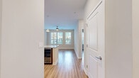 This well-designed single-floor residence offers a clean, modern aesthetic highlighted by warm wood-tone flooring that flows consistently throughout the entire space. The open-concept kitchen is a standout feature, equipped with stainless steel appliances, rich wood cabinetry, a white subway tile backsplash, and a generously sized granite-topped island with pendant lighting overhead. The kitchen opens seamlessly into the living and dining area, which is bathed in natural light from large windows with slatted blinds and features a ceiling fan overhead.

The bedrooms are spacious and well-lit, each offering multiple windows with outdoor views, ceiling fans, and the same continuous hardwood-style flooring. One bedroom includes access to a walk-in closet outfitted with a comprehensive built-in shelving and hanging system, providing ample organized storage.

The bathroom is thoughtfully appointed with a floating wood vanity, granite countertop, framed mirror, and chrome fixtures. A separate soaking tub with large-format neutral tile surround and a glass-enclosed shower round out the bathroom's functional design. The overall palette of warm beige tones, white trim, and natural wood accents creates a cohesive and inviting atmosphere throughout the residence.