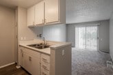 Located at 11902 Central Ave in Chino, CA, this two-bedroom, one-bathroom unit is thoughtfully laid out across a single floor, making efficient use of its cozy footprint. The open-concept kitchen flows directly into the living room, creating a connected and functional common area. The kitchen is equipped with stainless steel appliances—including a refrigerator, electric range, and over-the-range microwave—complemented by white cabinetry, light countertops, a double-basin sink, and wood-look flooring that adds warmth to the space. The living room features plush carpeting and a sliding glass door fitted with vertical blinds, allowing natural light to filter in and providing access to the outdoors. A textured ceiling runs throughout the common areas, adding a classic residential character. Both bedrooms are carpeted and neutral in tone, with built-in sliding closets offering practical storage. One bedroom features open wall shelving, while the primary bedroom is generously sized with a window dressed in horizontal blinds. The full bathroom is well-appointed with a white vanity, wood-look flooring, and a tub-shower combination. A hallway connects the main living areas to the bedrooms and bath, completing the straightforward and functional floor plan.